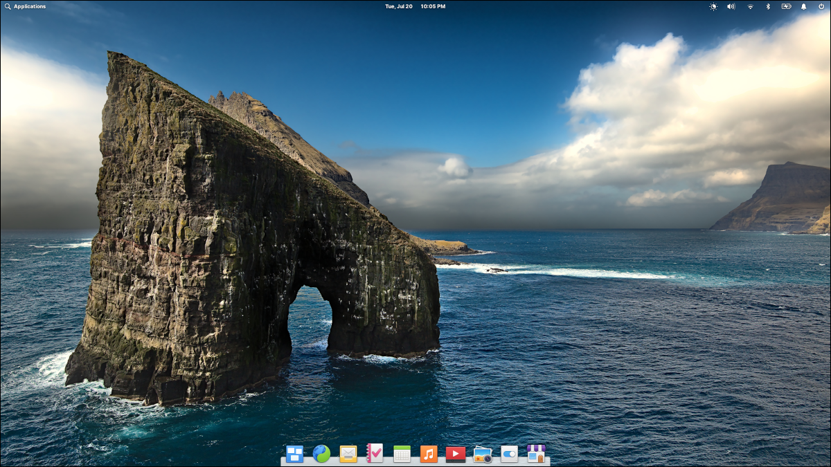 рабочий стол elementary OS 6 с обоями с изображением скалы в форме подковы в море.